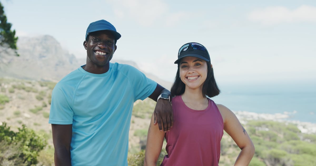 Portrait, hiking and interracial couple with smile for fitness, trekking or adventure on mountain
